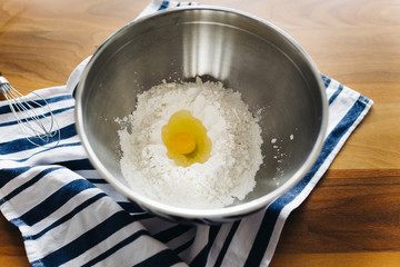 egg in flour at a metal bowl with brown background