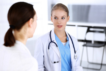 Doctor and patient during consultation. Physician at work filling up medication history record while sitting in emergency hospital, portrait shoot. Medicine and health care concept