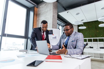 Two African business partners work in an office on a laptop