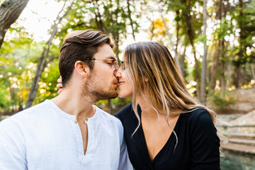 Fototapeta premium Man and woman in love in a park having a romantic kiss.