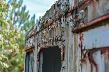 Detail of windows of an old abandoned rusty trailer covered with weathered curtains.