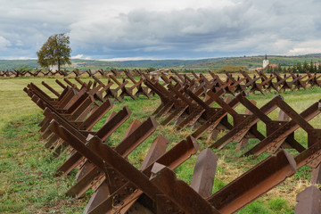 Lots of anti-tank obstacles (Czech hedgehogs) with lone tree and church in background © vasek.x1