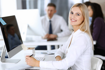 Fototapeta premium Business woman using computer at workplace in modern office. Secretary or female lawyer smiling and looks happy. Working for pleasure and success