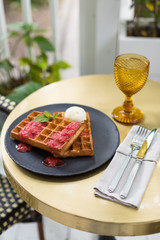 Golden waffles topped with fresh berry sauce and vanilla ice cream. Breakfast at restaurant.