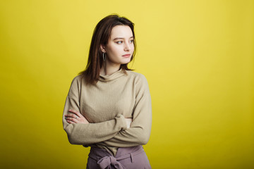 Obraz premium Image of a happy young girl standing isolated on a yellow background thinking about something