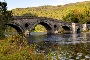 Fototapeta na wymiar Autumnal scene in Kenmore in Scotland. River Tay and bridge across road A827. Colorful scene. Orange colors in trees. Travel in Scotland.