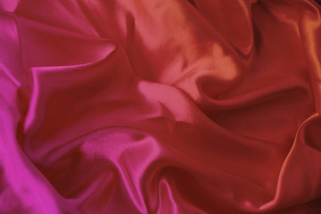 beautiful luxury texture of silk draped fabric with tints of pink, purple, top view, close-up, copy space