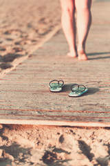 Bare feet of a girl walking on a wooden floor on the seashore.