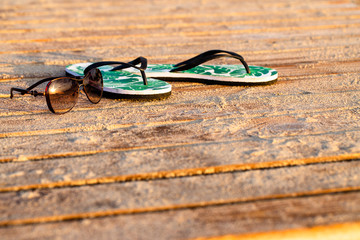 Green flip flops and sunglasses on the wooden boards