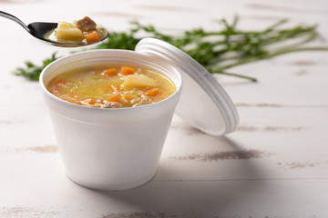 Vegetable soup in a disposable plastic bowl with a lid, on white background. Quick & easy food concept. Eating behavior, food delivery.