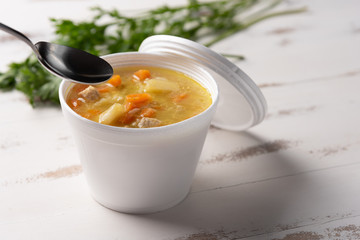 Vegetable soup in a disposable plastic bowl with a lid, on white background. Quick & easy food concept. Eating behavior, food delivery.