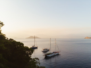 Evening sunset on the mediterranean sea. Luxury yachts lined up along the Turkish coastline, islands can be seen in the distant background. Beautiful scene shot aerially from a drone.