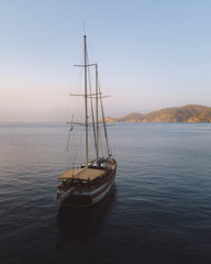 Traditional Turkish Gulets along the mountainous mediterranean coastline at sunset. The luxury boats dock against the cliffs for the night for shelter from the winds. Aerial drone shot from above. 