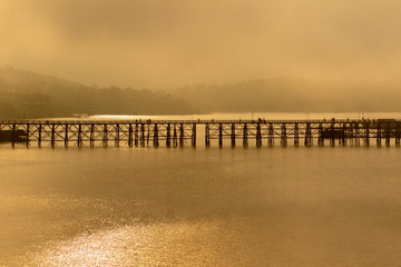 Fototapeta premium foggy of sangkhalburi wooden bridge one of most popular traveling destination in kanchanaburi western of thailand