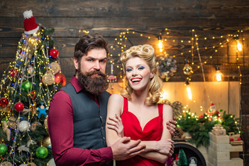 Happy Christmas couple in evening dress with red gift box over home Christmas tree background. Fashion and beauty make-up and hairstyle for Christmas.