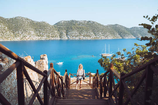 Lone girl taking in the views from on top the Kalekoy castle. The beautiful blue mediterranean water and mountains are in the background.