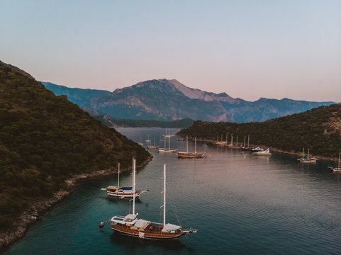 The sun setting over a quiet bay near Fethiye, Turkey. The traditional Turkish gulets line the shore with the mountainous coastal landscape in the background. 