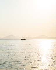 Naklejka premium A lone traditional gulet sailing near Fethiye, Turkey. The mountainous coastal landscape can be seen in the distant background. 