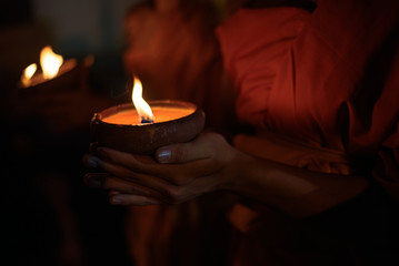 Buddhist monk hands holding candle cup in the dark   ,Chiang mai , Thailand - obrazy, fototapety, plakaty