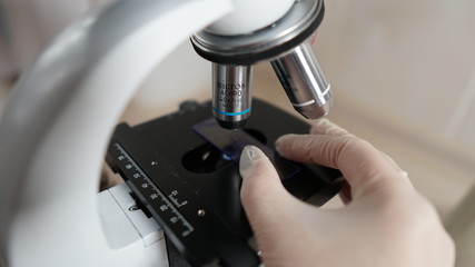 Laboratory technician makes fine-tuning of the microscope to study the samples