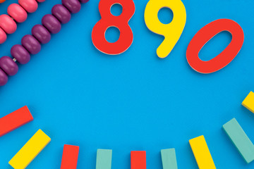 Top view on children's educational games, frame from multicolored kids toys on blue paper background. Wooden bricks, numbers, scores. Flat lay, copy space for text