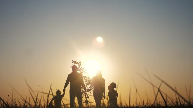 happy family walking agriculture of farmers a silhouette concept slow motion video. mom dad son and daughter walk go children plant and water the tree outdoors in the park. happy family mother and