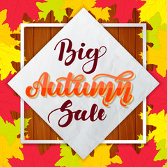 Big autumn sale. Lettering on wooden background with colorful maple leaves. Template for advertising banners, posters, flyers.