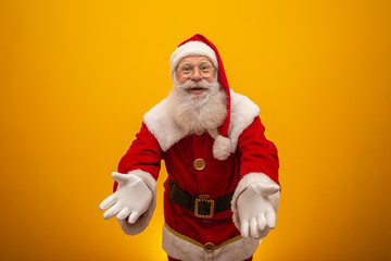 Fototapeta na wymiar Santa Claus on yellow background with copy space. Presenting.