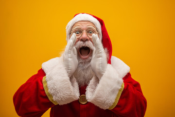 Communication concept. Profile side view photo of excited funny kind stylish Santa Claus with open mouth hold palm hand near face saying loud ho-ho-ho isolated on vivid yellow background