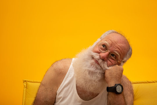 Old man with a long beard on a yellow background. Senior with full white beard. Old man with a long beard with sadness.
