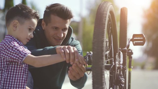 The father teaching his son to fix the bicycle. slow motion