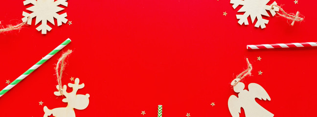 Christmas composition. Paper straws, wooden toys lying on red background. new year concept. Horizontal long banner for web design. Greeting card, winter holidays, xmas celebration 2020. Flat lay, top