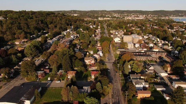 An early evening forward aerial establishing shot of a residential neighborhood in the Pennsylvania hills. Pittsburgh suburbs. Ohio River in the far distance.  	