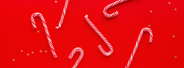 Christmas composition. Candy canes on red paper background. Horizontal long banner for web design. Minimal new year concept. Greeting card, winter holidays, xmas celebration 2020. Flat lay, top view