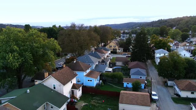 A dusk forward aerial view of homes in Western Pennsylvania in the early Autumn. Backs of houses, alley view. Pittsburgh suburbs.  	