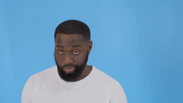 Closeup portrait of skeptical young man looking suspicious and some disgust on his face, mixed with disapproval, isolated on blue background. Negative human emotion, facial expressions, feelings 4K
