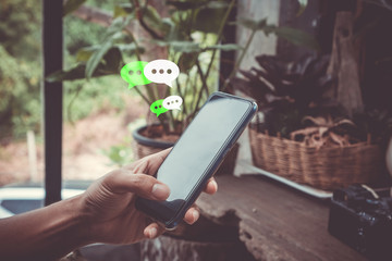 Women hand using smartphone typing, chatting conversation in chat box icons pop up. Social media maketing concept.