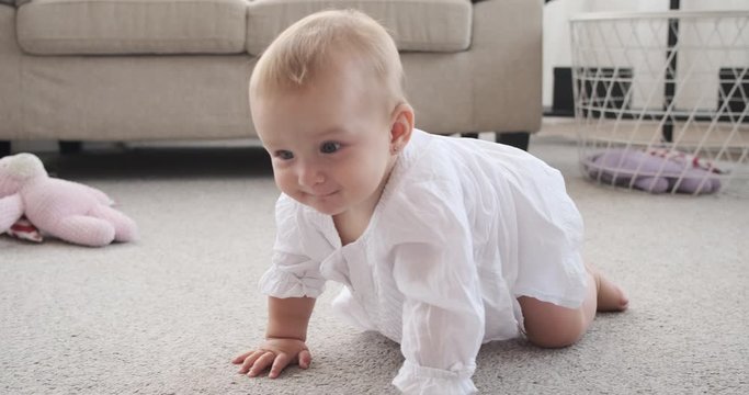 Cute baby girl learning to crawl on carpet at home