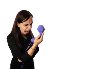 A beautiful emotional woman in a black dress is yelling in a handset on isolated white background. Copy space.