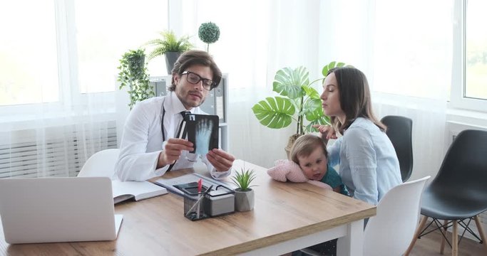 Doctor explaining xray image to mother with little daughter at clinic