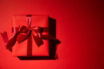 Top view of red christmas boxes with red ribbon on red background with copy space for text. black Friday and Boxing Day composition.