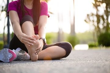 Young woman massaging her painful foot while exercising. Running Sport and excercise injury concept.