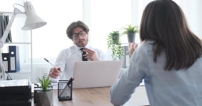 Young businesswoman trying to defend herself in meeting with boss at office