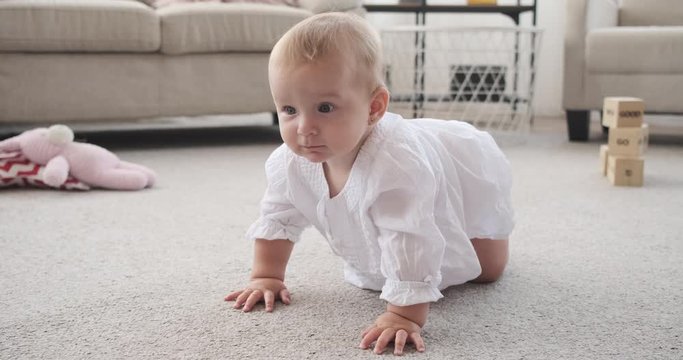 Cute baby girl learning to crawl on carpet at home