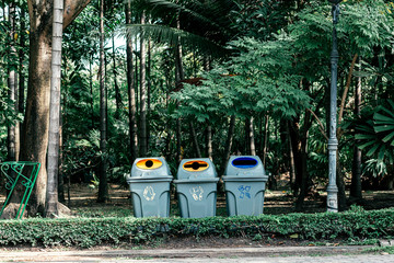 Horizontal shot of recycling bins in green park or forest. Colour and sign on bin indicates different type of garbage and makes the waste sorting process easier. Environmental protection concept