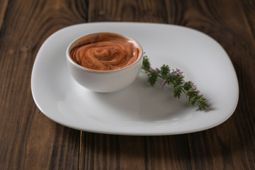 Red and white hot sauce with spicy grass on a white plate. Vegetarian sauce.