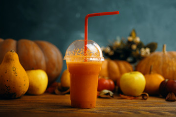 Pumpkins juice in bottles with pumpkins. Glass of fresh pumpkin smoothie on wooden background
