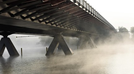 steam from the river under the bridge in the early morning