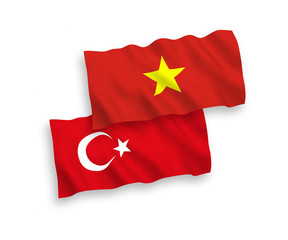 National vector fabric wave flags of Turkey and Vietnam isolated on white background. 1 to 2 proportion.