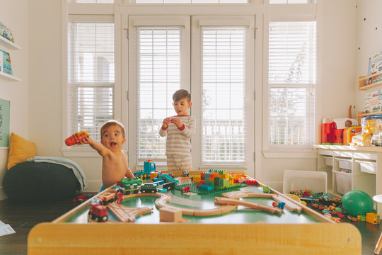 Two Children Playing In A Messy Playroom.